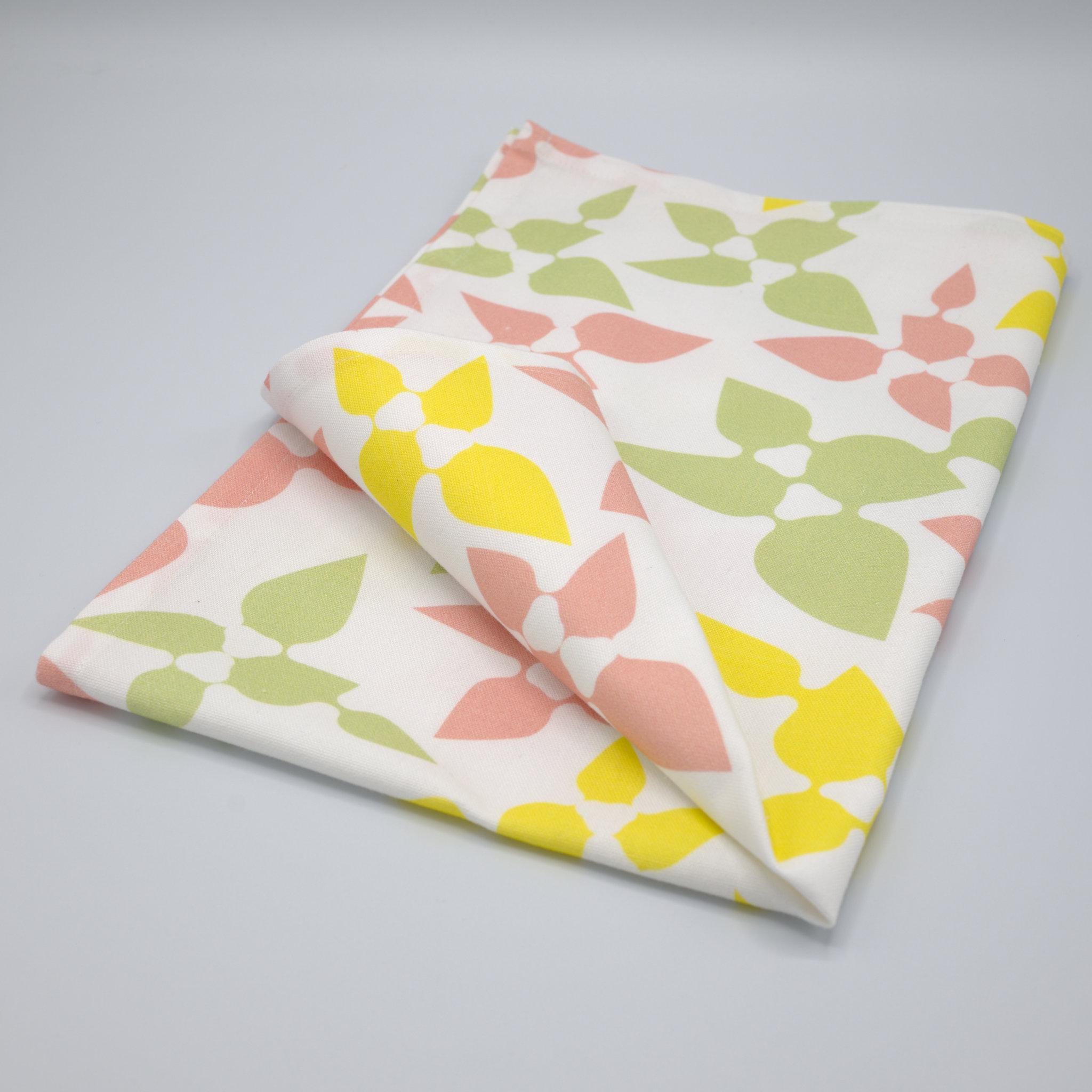 celebration tea towel folded with leaf patterns on a gray background from Hem And Tassel 