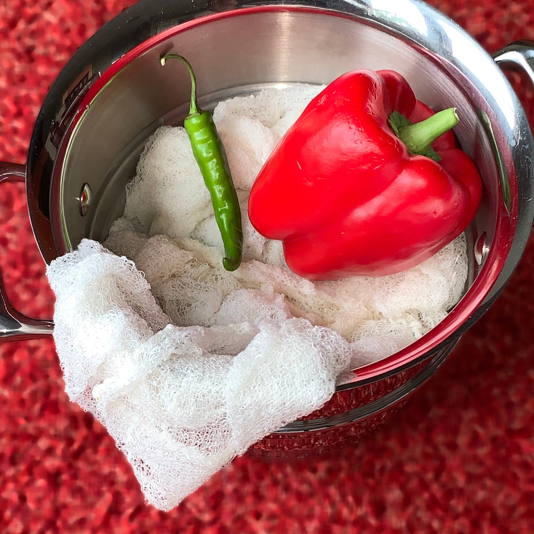 Certified Organic Cheesecloth in a vessel with peppers on a red textured background from Hem And Tassel 