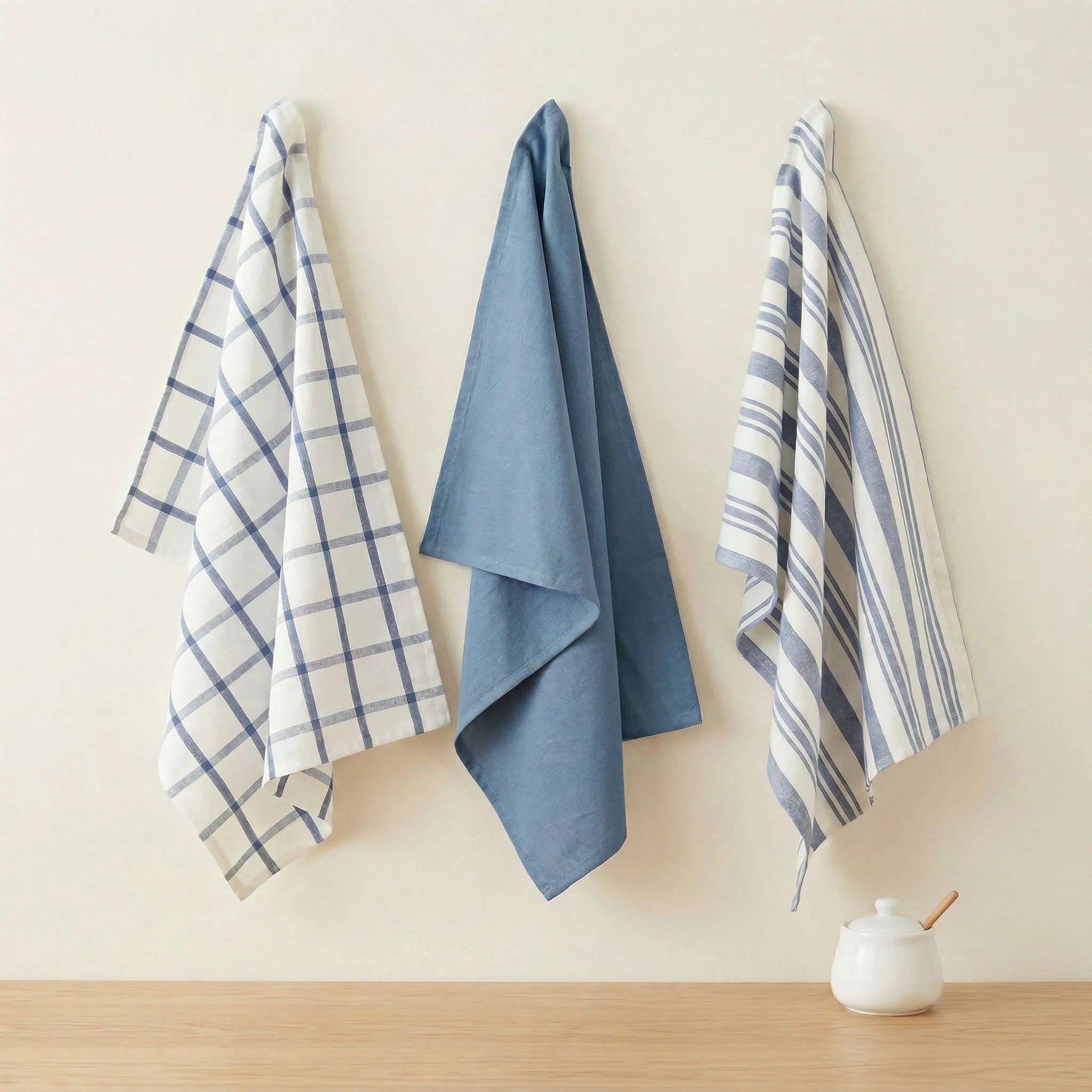 decade classics blue - set of three kitchen towels of 100% cotton -  hanging against a cream backdrop from Hem And Tassel 