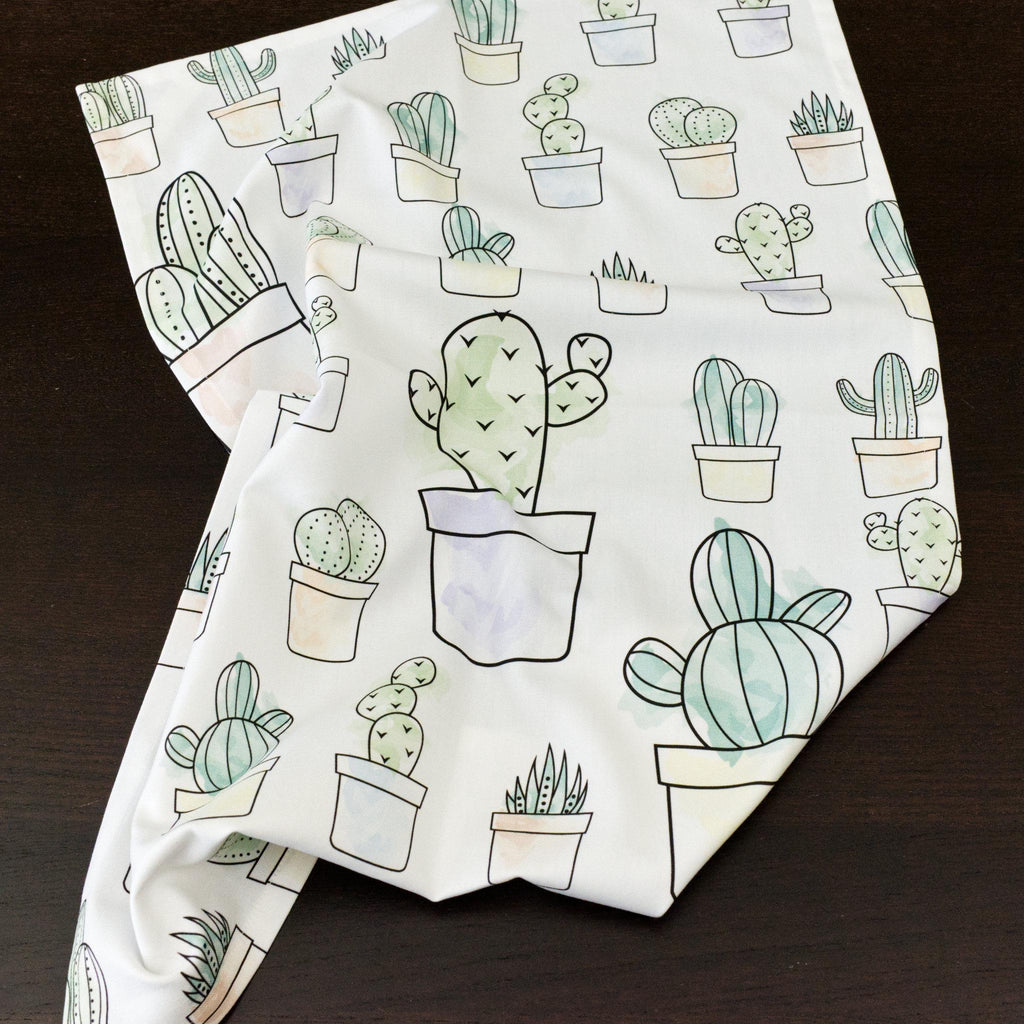 desert haze tea towel with cactus pattern mussed up on a dark surface from Hem And Tassel 