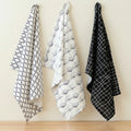 crinkled flour sack - set of three 100% cotton kitchen towels in black and white designer prints;, hanging against a cream backdrop, from Hem And Tassel