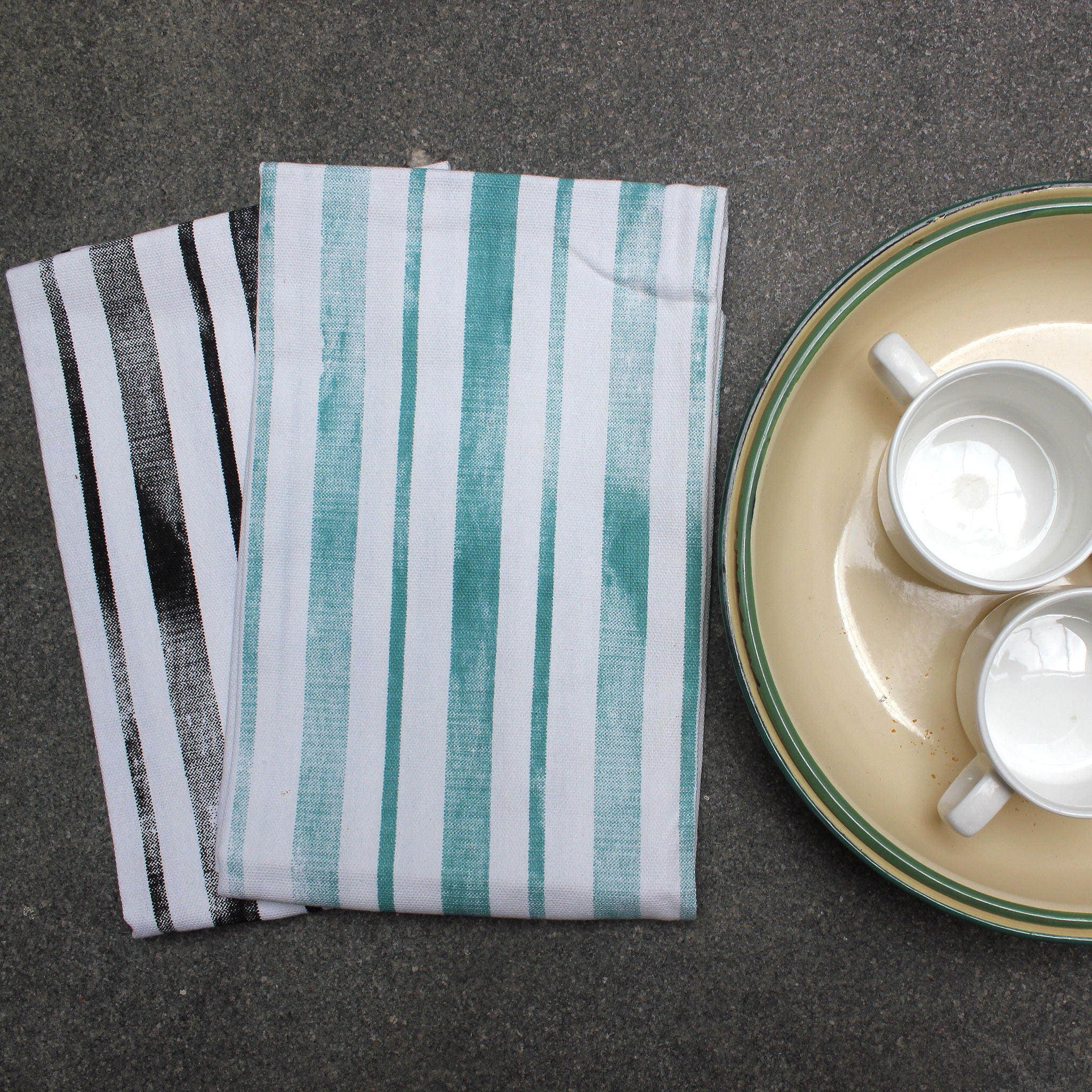 distressed Stripes kitchen towels with a plate containing two ceramic cups on a dark surface from Hem And Tassel 