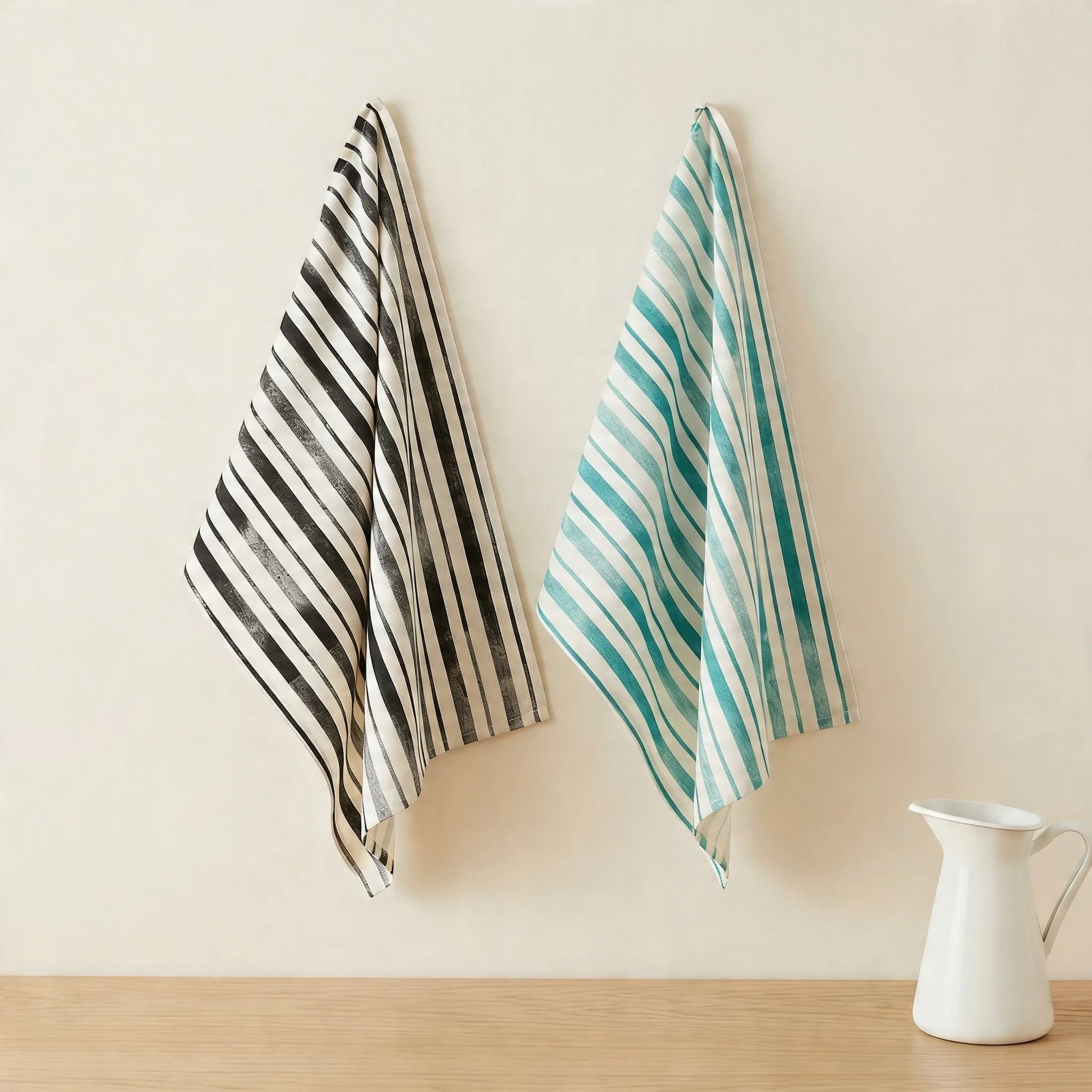 distressed strips kitchen towels of 100% cotton in a set of two - one charcoal and one green, hanging against a cream colored backdrop from Hem And Tassel
