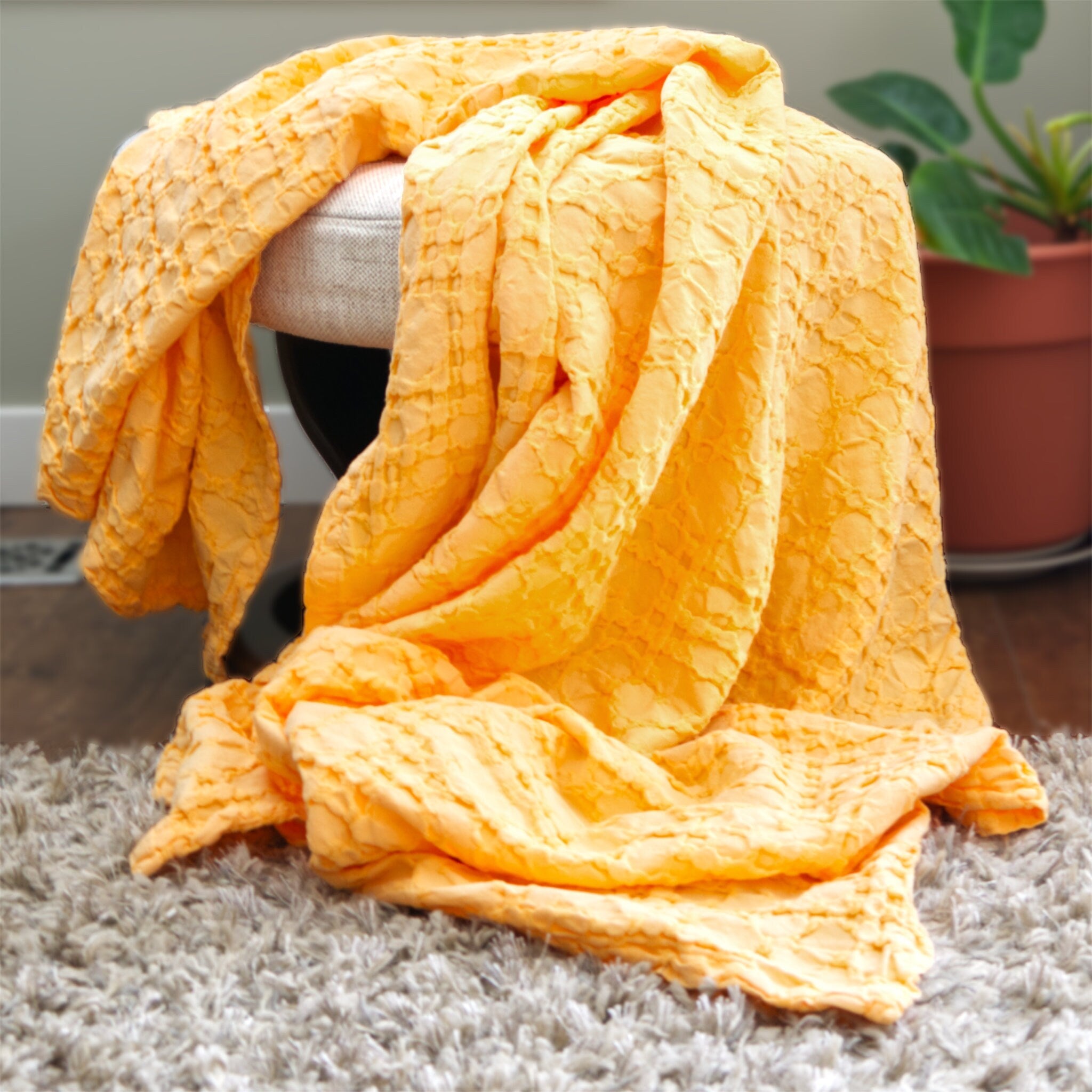 Yellow textured wearable throw draped over a chair with a plant in the background