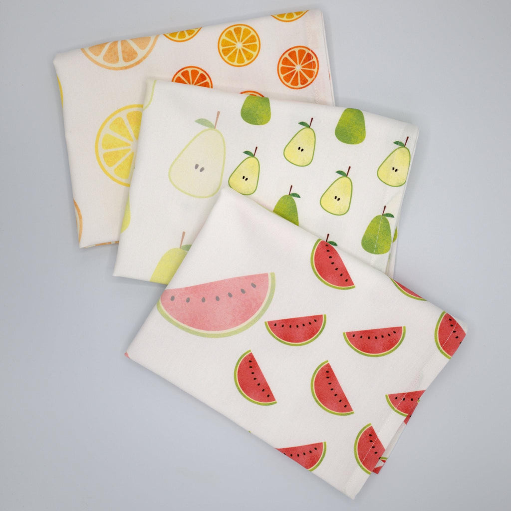 Three faded fruit kitchen towels with fruit patterns on a gray background from Hem And Tassel 