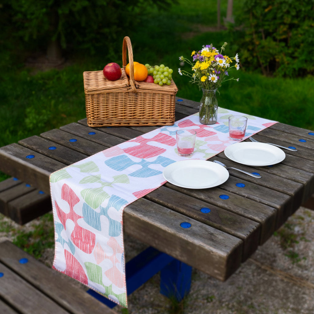Colorful patterned flock and flutter table runner  on a wooden bench outdoors from Hem And Tassel 