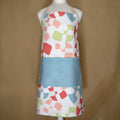 mannequin wearing Colorful flock and flutter patterned cotton apron with a turquoise pocket from Hem And Tassel, on a beige background