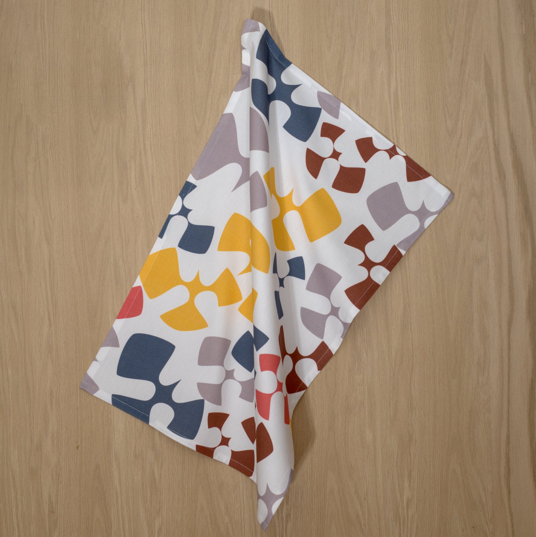 Colorful patterned Flock and Flutter design tea towels on a wooden surface from Hem And Tassel 