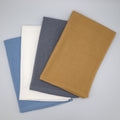 Four textured Jekyll and Hyde kitchen  towels in blue, white, gray, and camel yellow on a light gray background seen with waffle side up