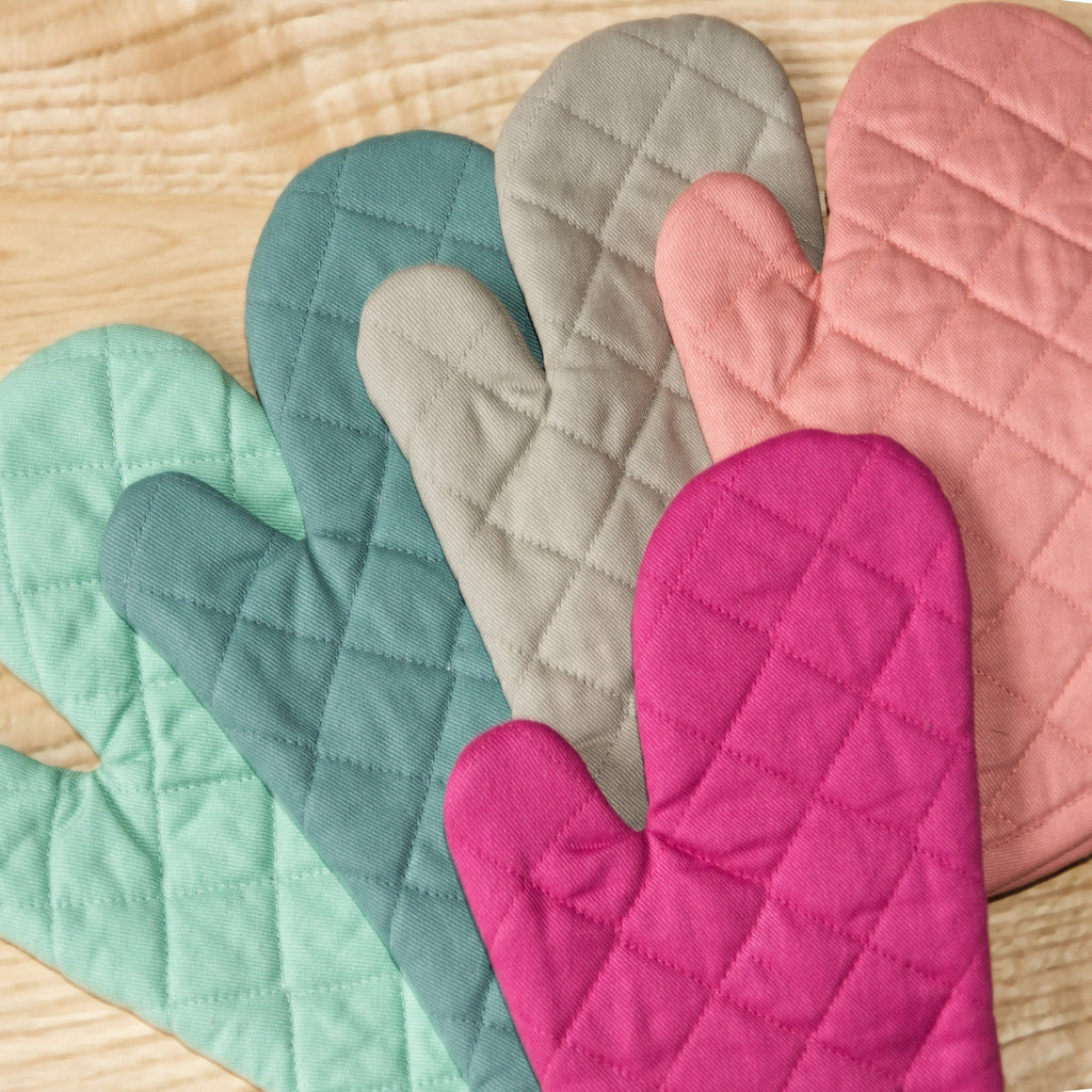 Set of colorful quilted oven mitts on a wooden surface