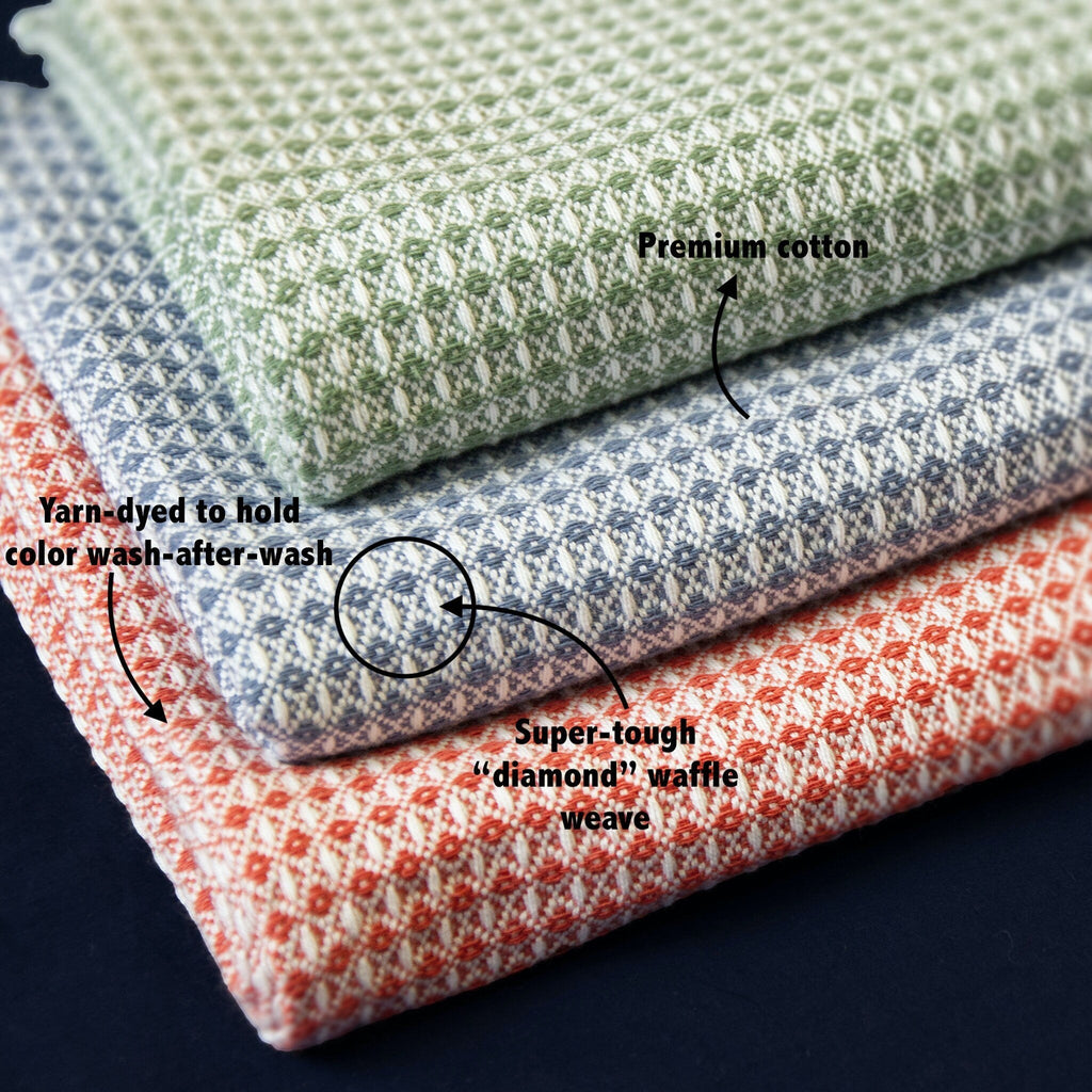 Hem And Tassel diamond waffle weave cotton cloths in sage green, blue, and terracotta stacked for kitchen or bath use.