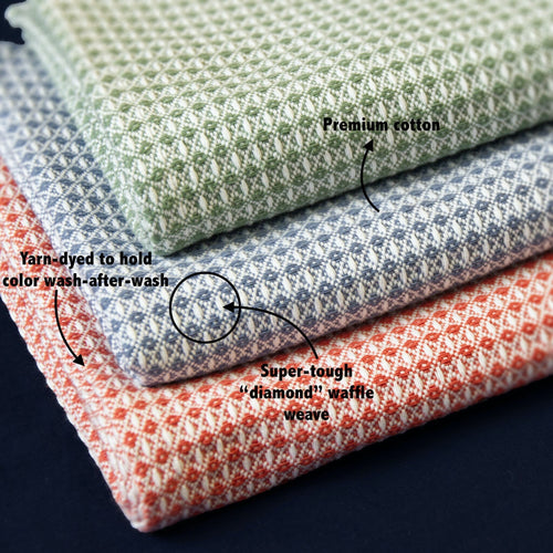 Hem And Tassel diamond waffle weave cotton cloths in sage green, blue, and terracotta stacked for kitchen or bath use.