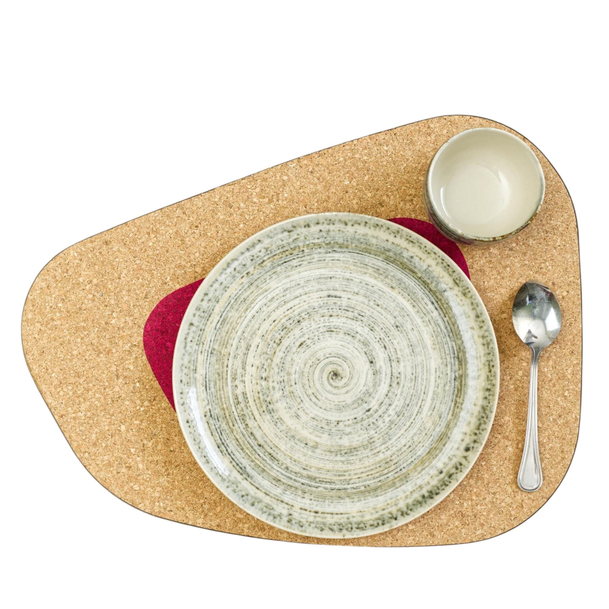 Hem And Tassel oversize kidney bean shaped natural cork placemat with a decorative plate, bowl, and spoon