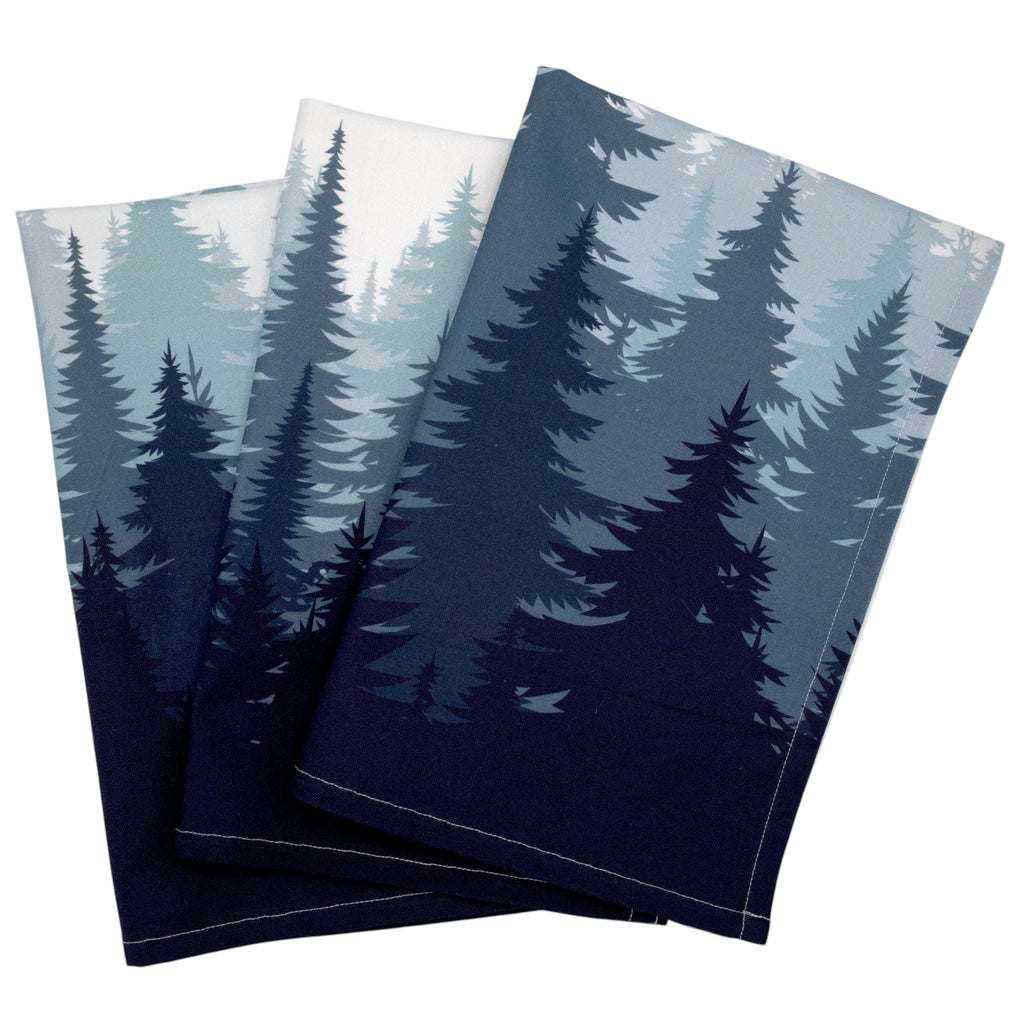 Hem And Tassel set of three cotton kitchen towels featuring an ombré pine forest print in shades of blue and white.