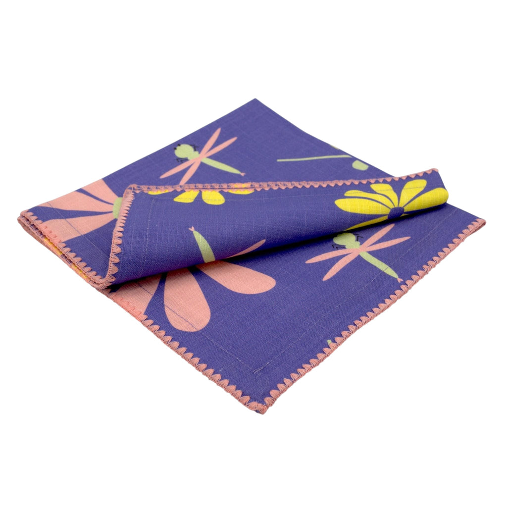 Hem And Tassel purple slub cotton dinner napkin with a playful dragonfly and floral pattern and pink stitched edges