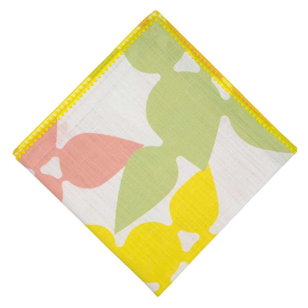 Hem And Tassel Celebration slub cotton dinner napkin with green, pink, and yellow leaf print and yellow trim.