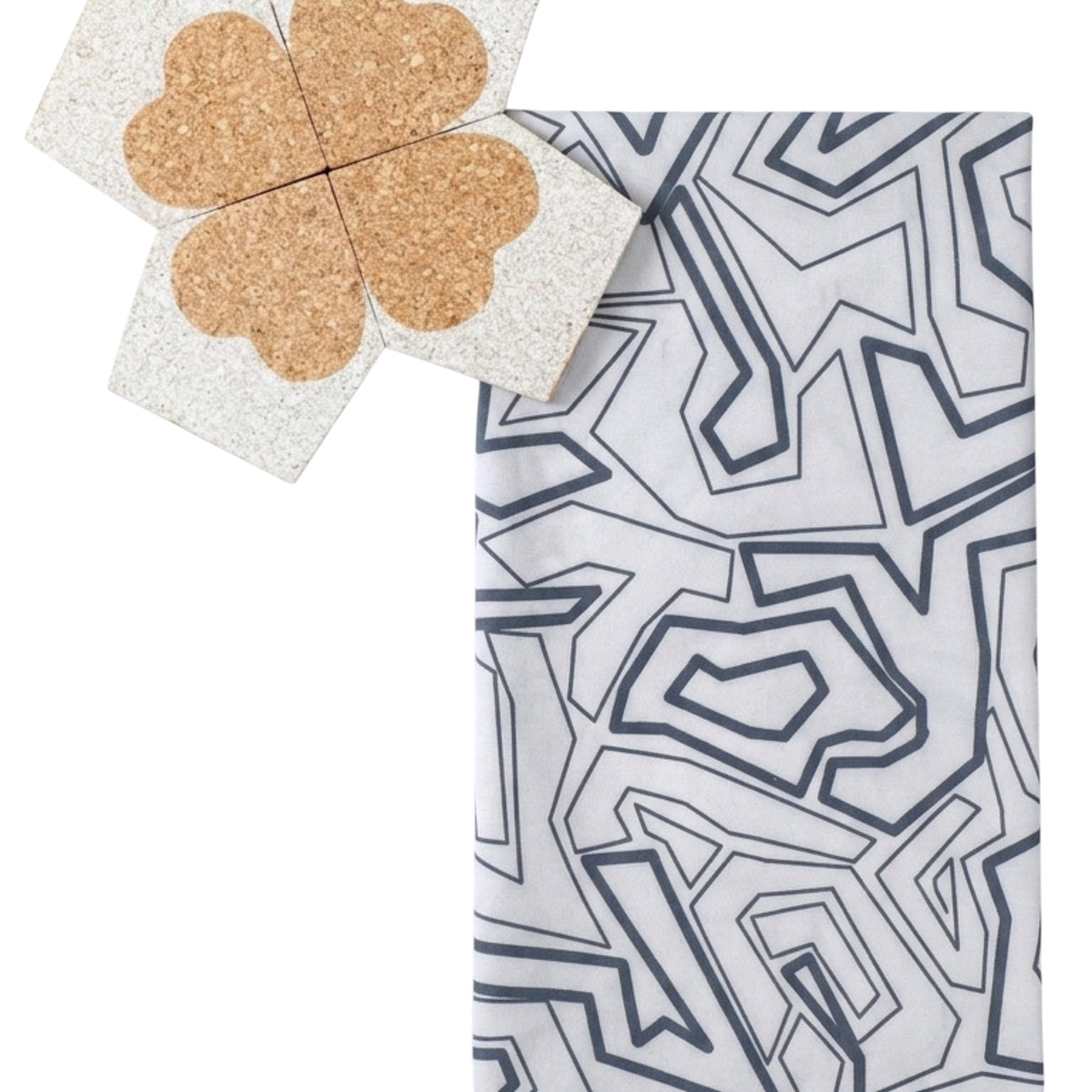 Hem And Tassel Squiggles cotton kitchen towel with grey geometric pattern next to a four-leaf clover cork coaster.