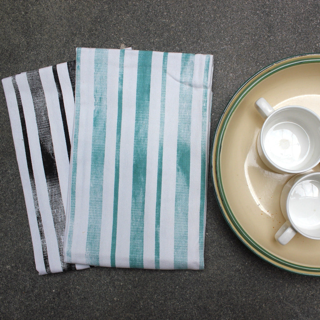 Hem And Tassel kitchen towel bundle featuring one black and white striped towel and one green and white striped towel.