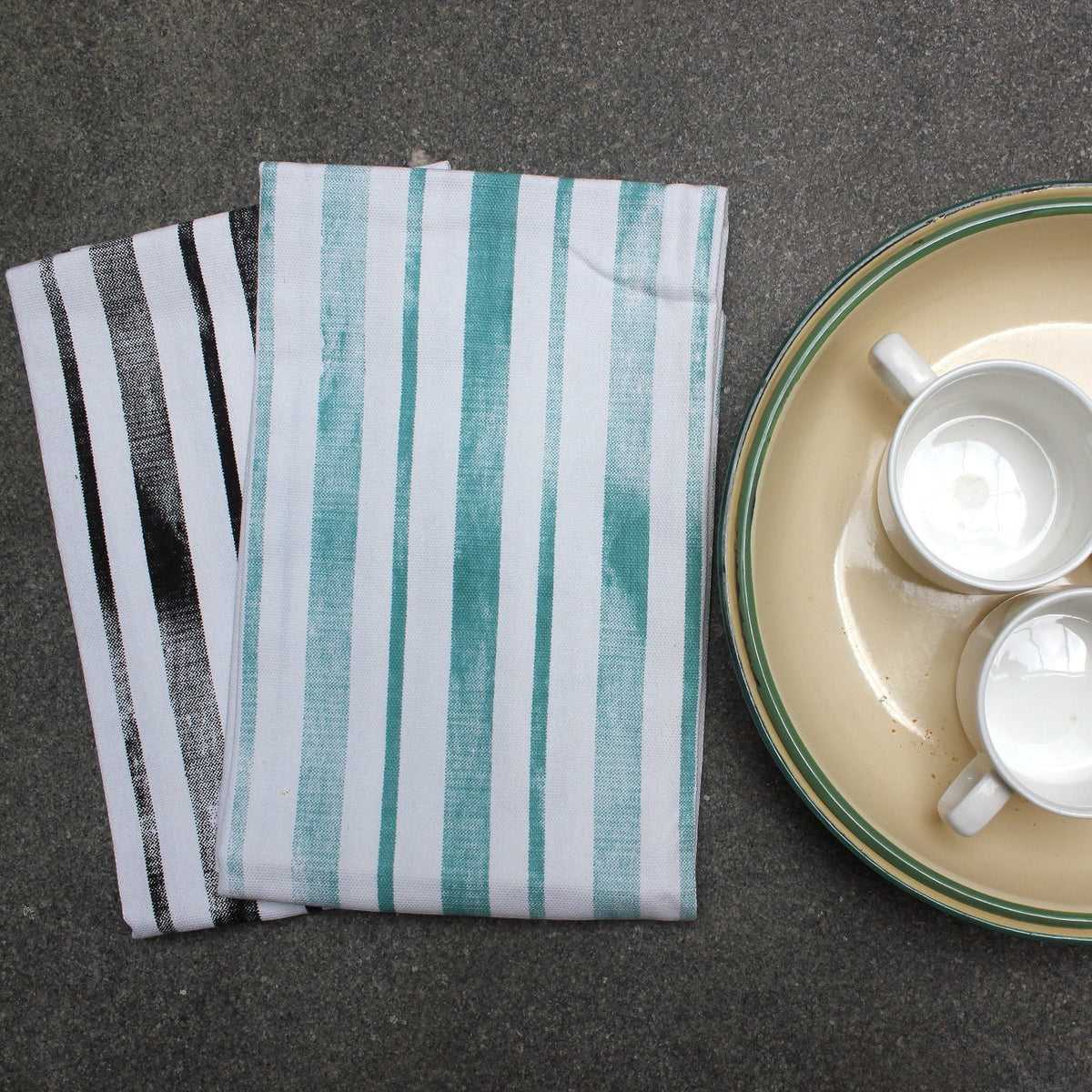 Hem And Tassel kitchen towel bundle featuring one black and white striped towel and one green and white striped towel.
