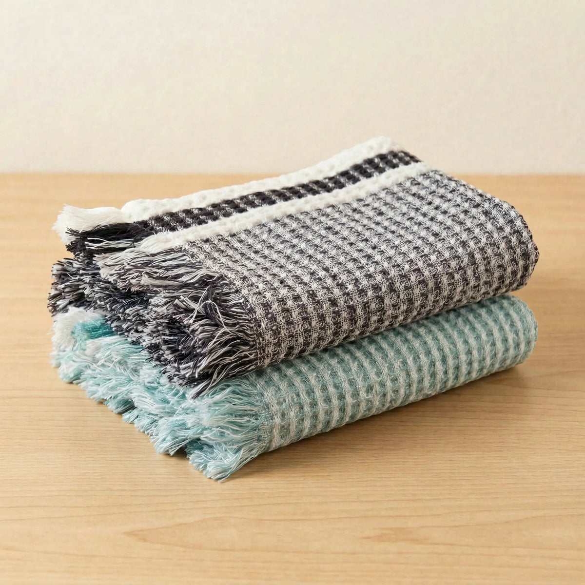 Hem And Tassel kitchen towel bundle featuring one graphite grey and one grass green waffle-weave towel with fringe.