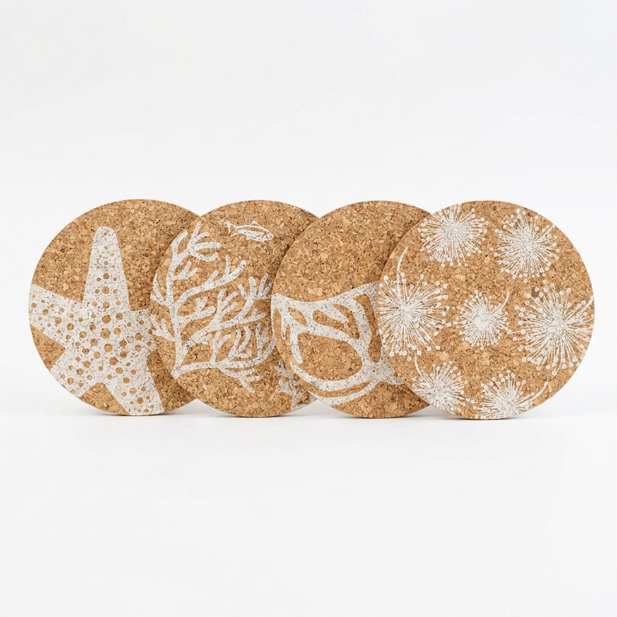 Four round cork coasters with white marine-themed prints, including a starfish, coral, and sea urchins, arranged in a row on a white background from Hem And Tassel 