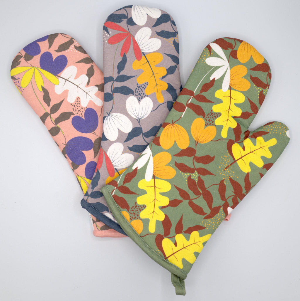Three just leaves floral-patterned oven mitts in different colors on a light gray background from Hem And Tassel 