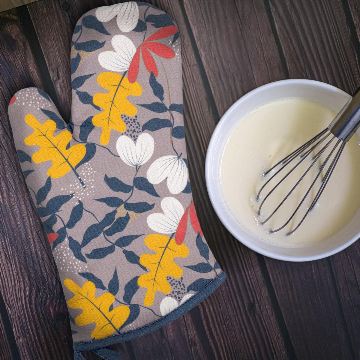 quilted and wadded cotton oven mitt in orange oak of just leaves design  on kitchen table with beaten egg and whisk nearby - from Hem And Tassel