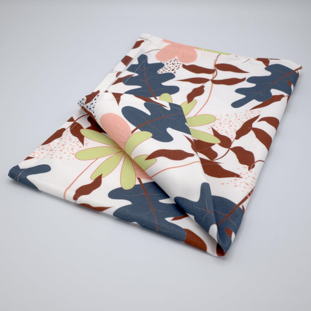 Folded just leaves tea towel with a colorful leaf pattern on a light gray background from Hem And Tassel 