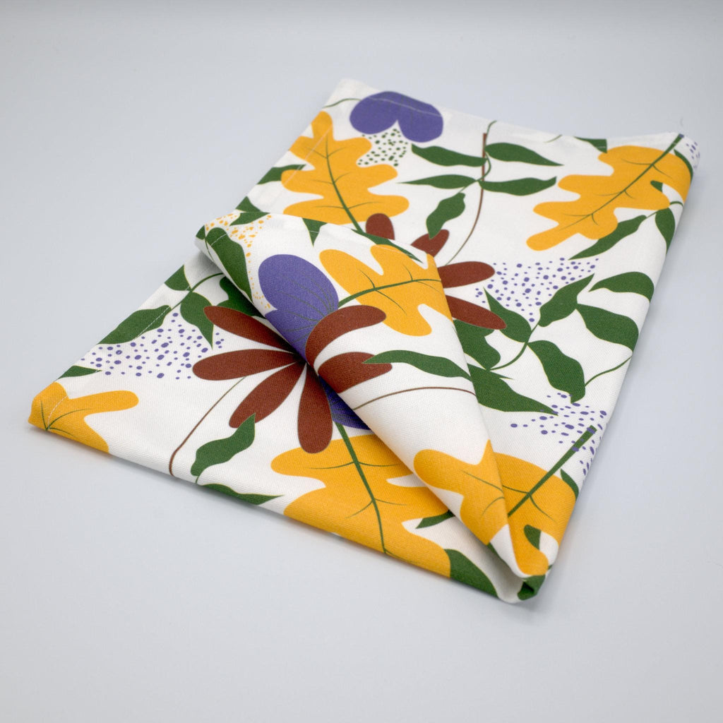 Folded just leaves tea towel with colorful orange oak leaf  pattern on a gray background from Hem And Tassel 