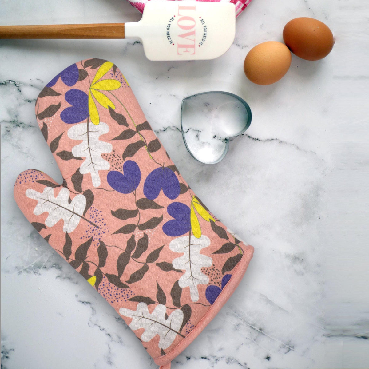 just leaves-patterned oven mitt on a marble surface with eggs and a spatula from Hem And Tassel