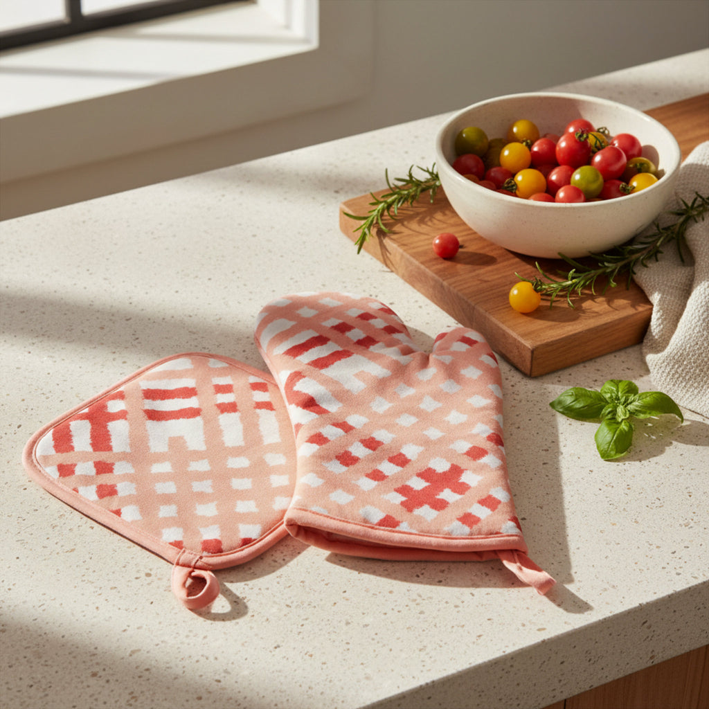 blush and pink and white patterned oven mitt and pot holder on a light speckled countertop, with a white bowl of cherry tomatoes and basil in a kitchen setting from Hem And Tassel 