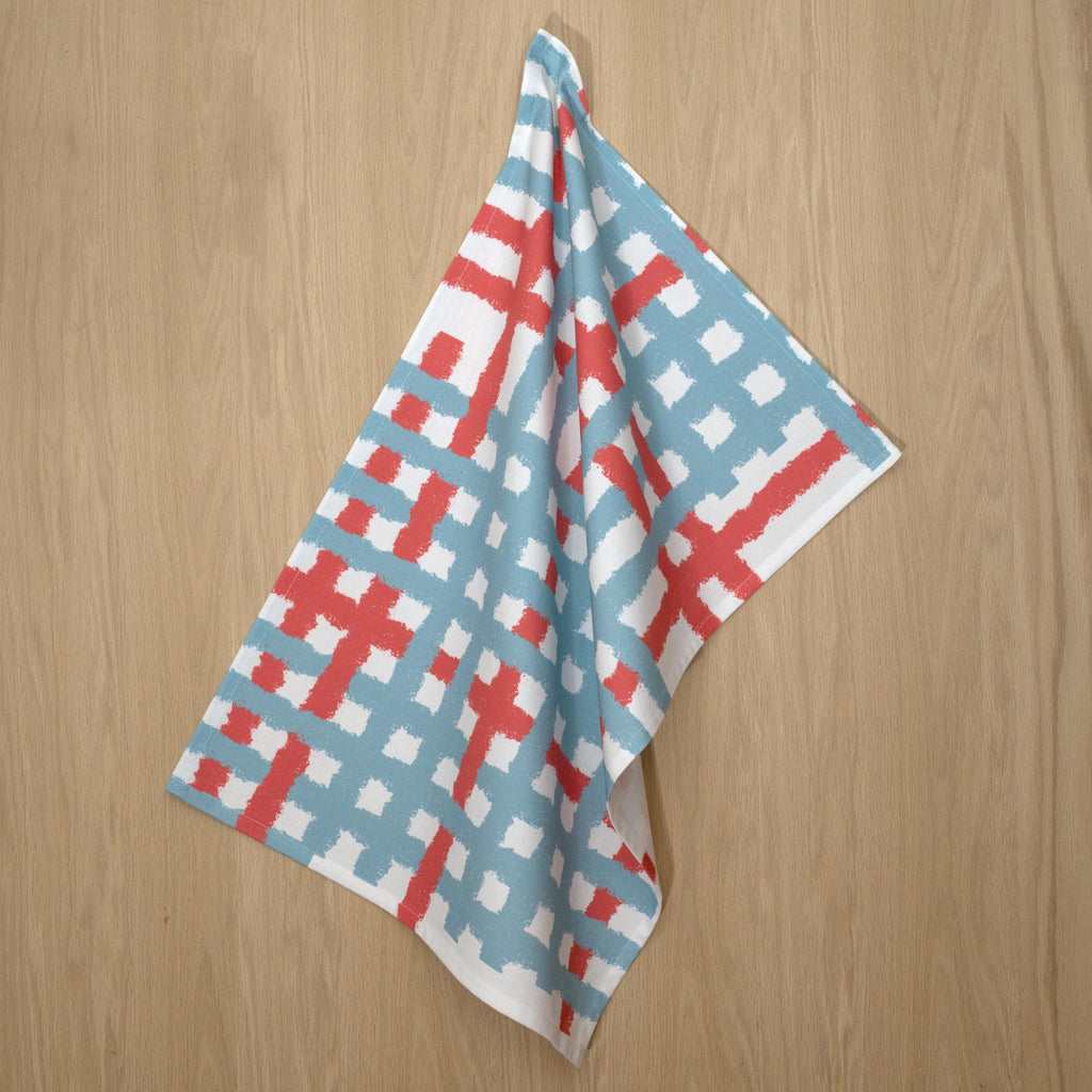 Hanging cotton tea towel with pink and blue jute impossible pattern from Hem And Tassel on a wood background