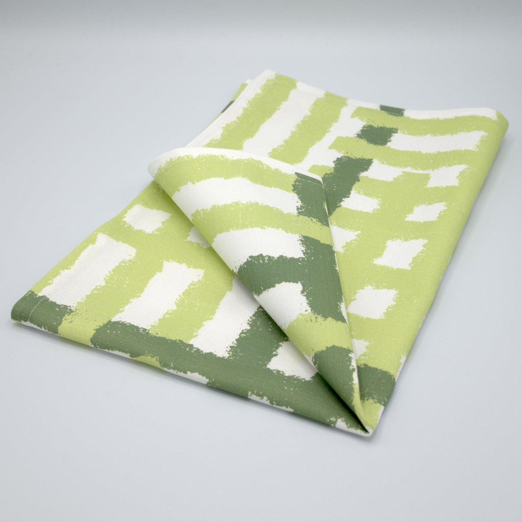 Folded cotton tea towel with green and white jute impossible pattern from Hem And Tassel on a gray background
