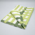 Folded cotton tea towel with green and white jute impossible pattern from Hem And Tassel on a gray background