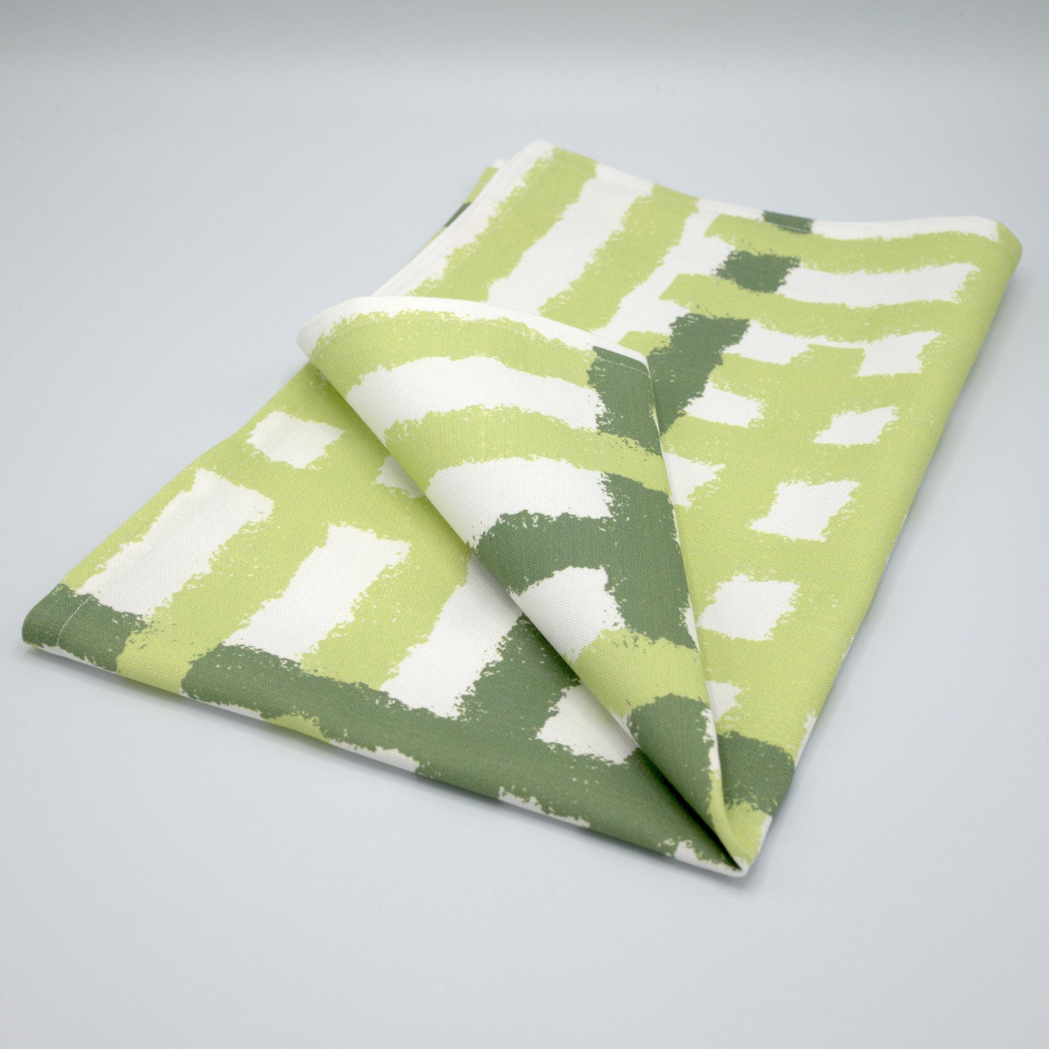Folded cotton tea towel with green and white jute impossible pattern from Hem And Tassel on a gray background