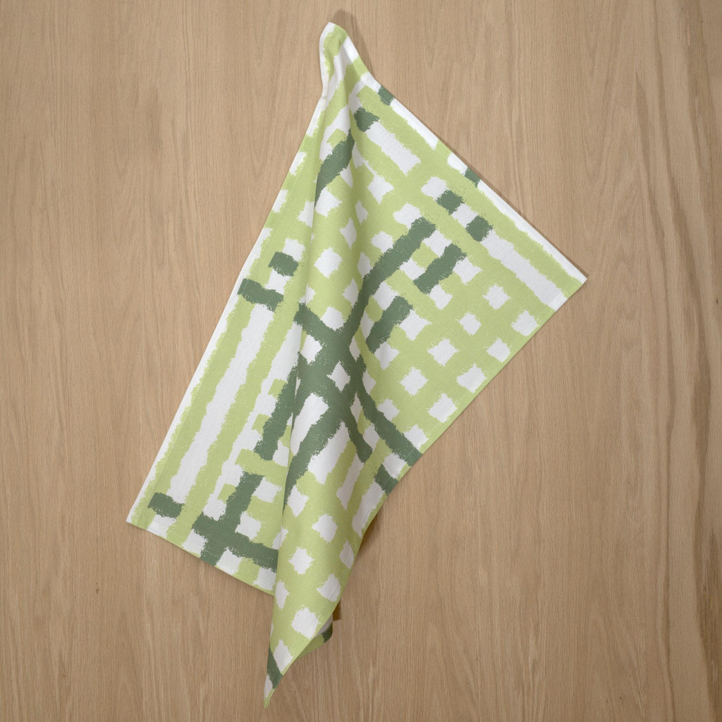 Hanging cotton tea towel with green and white jute impossible pattern from Hem And Tassel on a wood background