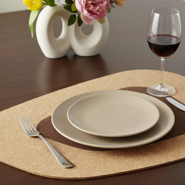 Dining table setting with plates, wine glass, and flowers on a wooden surface on a kidney bean cork placemat from hem and tassel