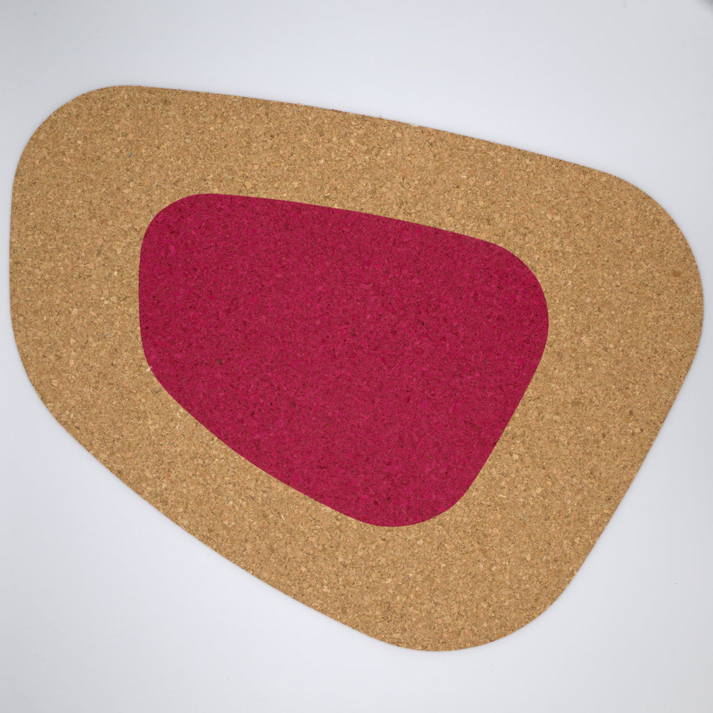 a kidney bean shaped large cork placemat with a wine color block on a white background