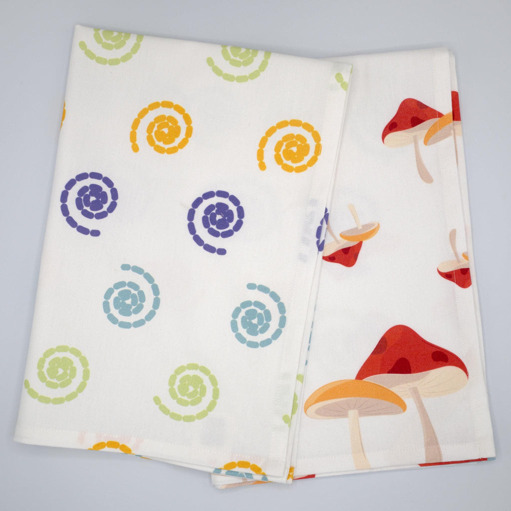 cotton percale tea towel in magic and mushroom designs from Hem And Tassel, with colorful swirls, folded on a light grey background