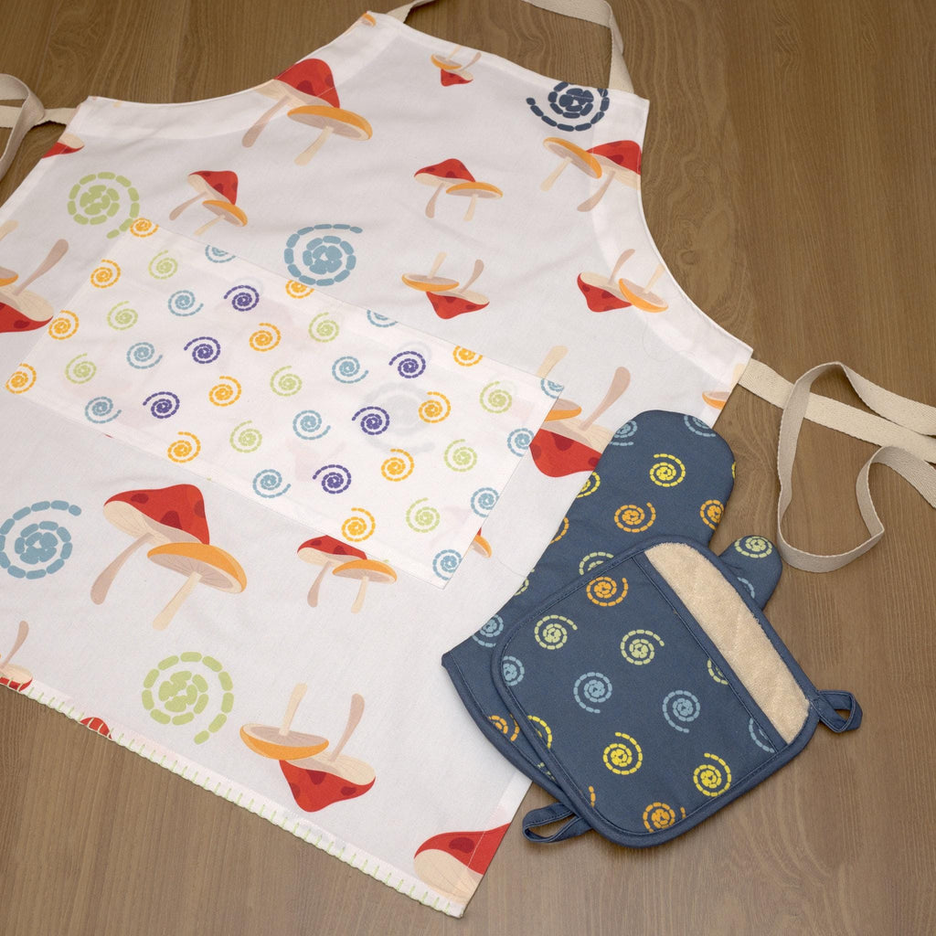 Colorful mushroom magic cotton apron with matching oven mitt and pot holder from Hem And Tassel, on a wooden surface