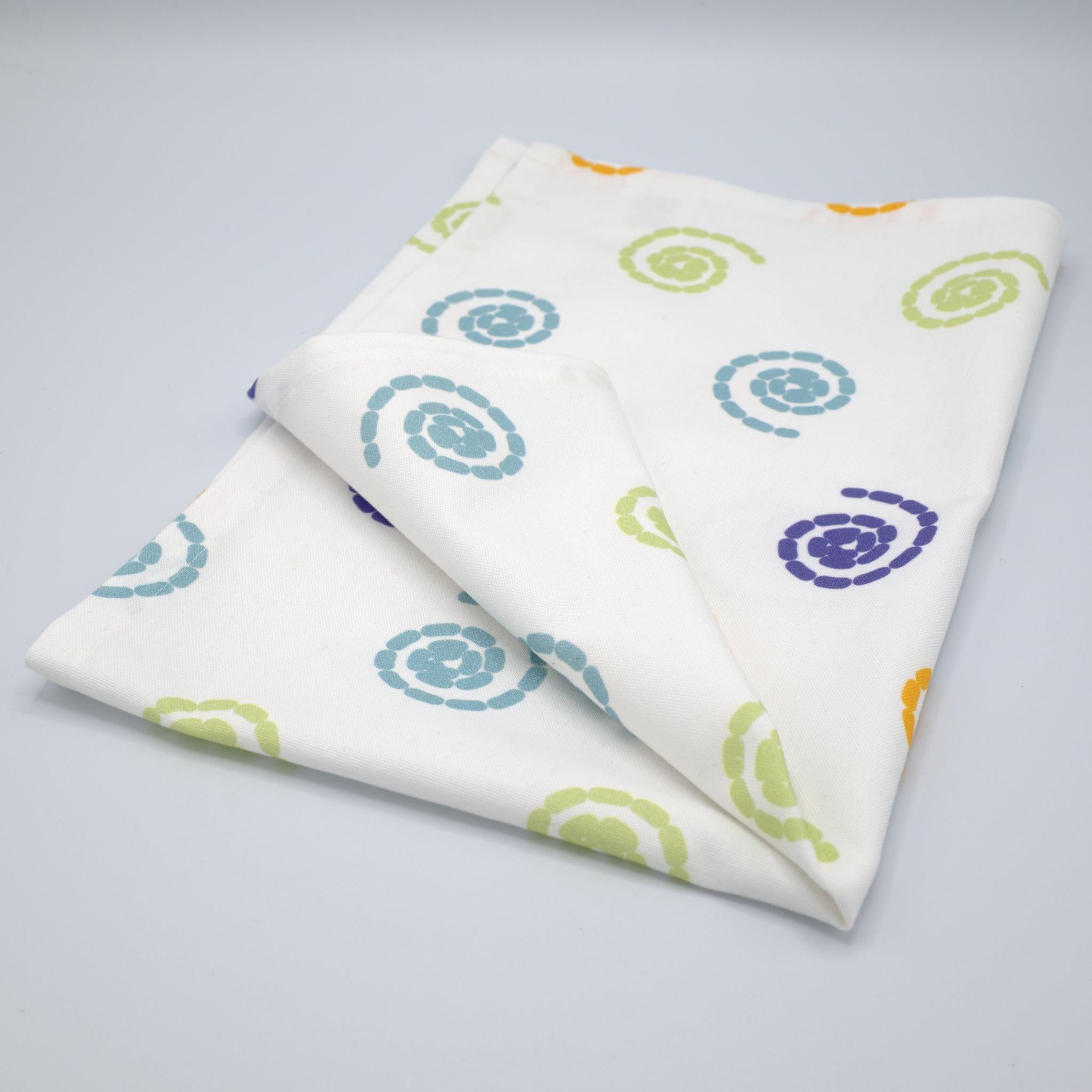 cotton percale tea towel in magic design from Hem And Tassel, with colorful swirls, folded on a light grey background