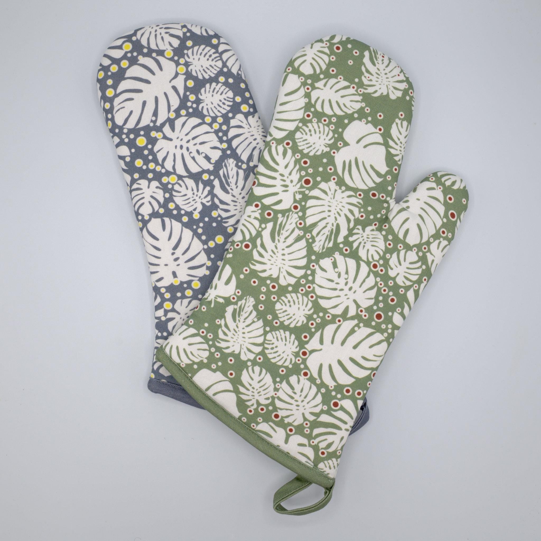 Two monster-ah oven mitts with leaf patterns on a light gray background from Hem And Tassel 