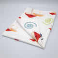 cotton percale tea towel in mushroom design from Hem And Tassel, with colorful swirls, folded on a light grey background