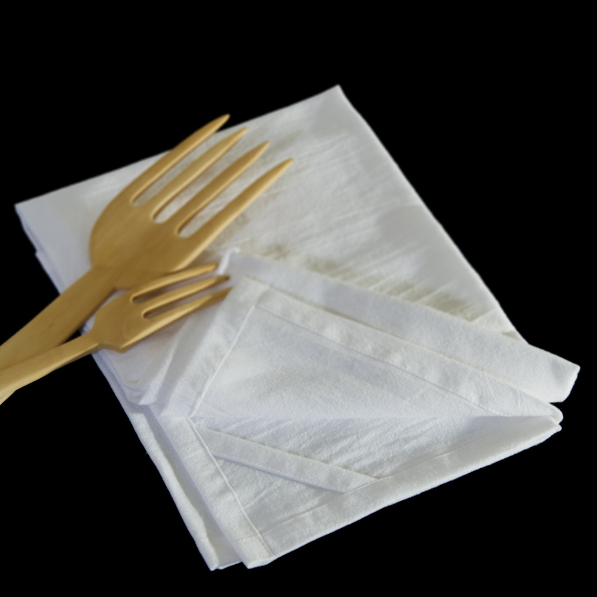 plain white flour sack folded cotton towel with wood forks on a black background from Hem And Tassel 