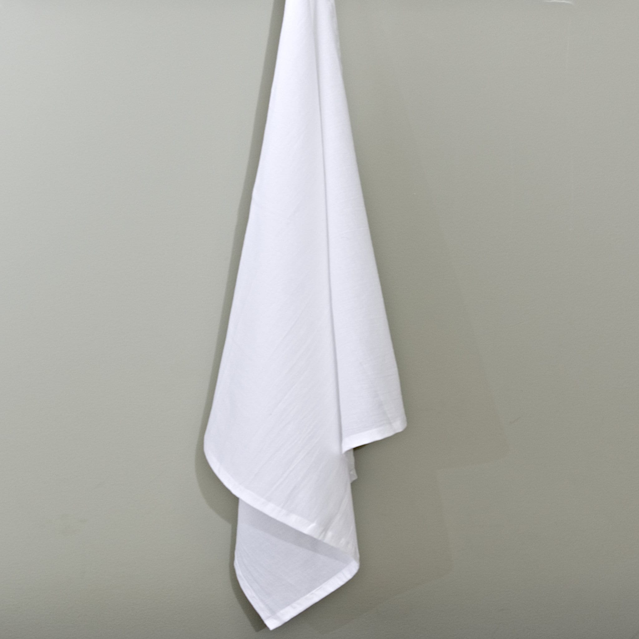 plain white flour sack hanging cotton towel on a grey background from Hem And Tassel 