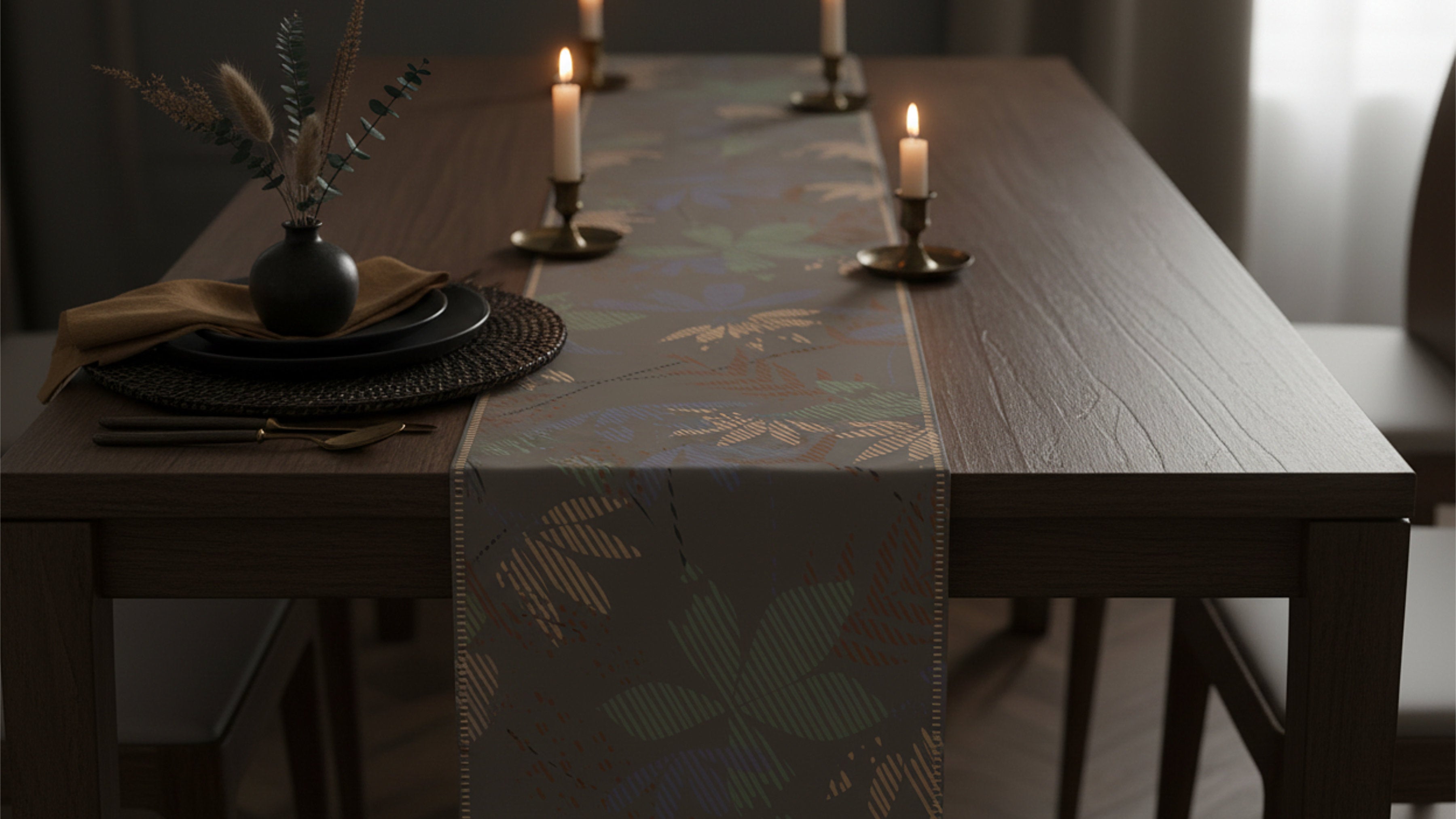 A dark wood dining table set with a patterned table runner, place settings, and lit candles in a dimly lit interior.