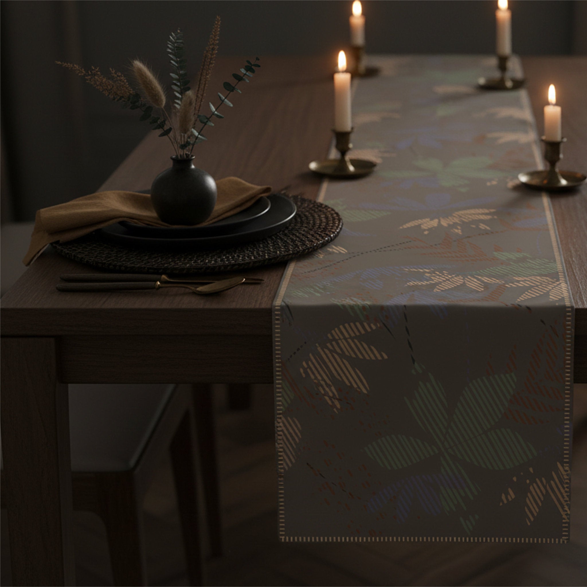 A dark wood dining table styled with a patterned table runner, place settings, and lit candles in a dimly lit room from Hem And Tassel 