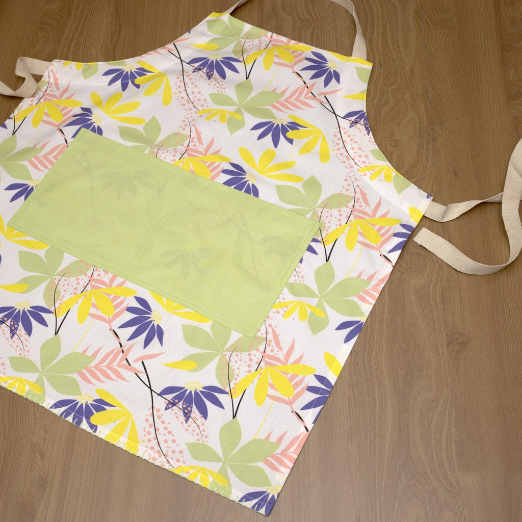 Colorful floral-patterned pollen up apron on a wooden surface from Hem And Tassel 