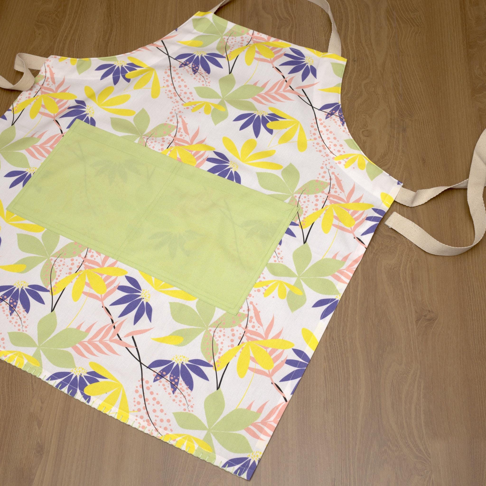 Colorful floral-patterned pollen up apron on a wooden surface from Hem And Tassel 