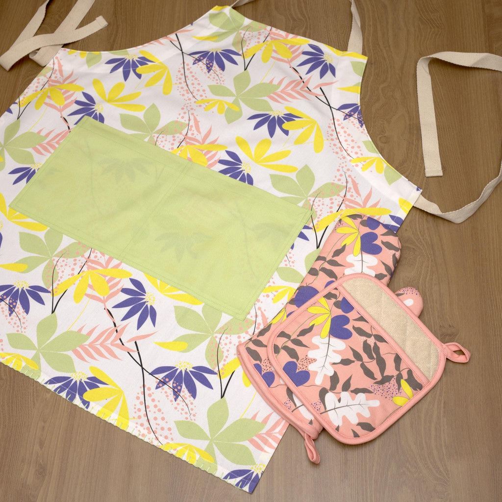 Floral pollen up apron with matching oven mitt and pot holder on a wooden surface from Hem And Tassel 